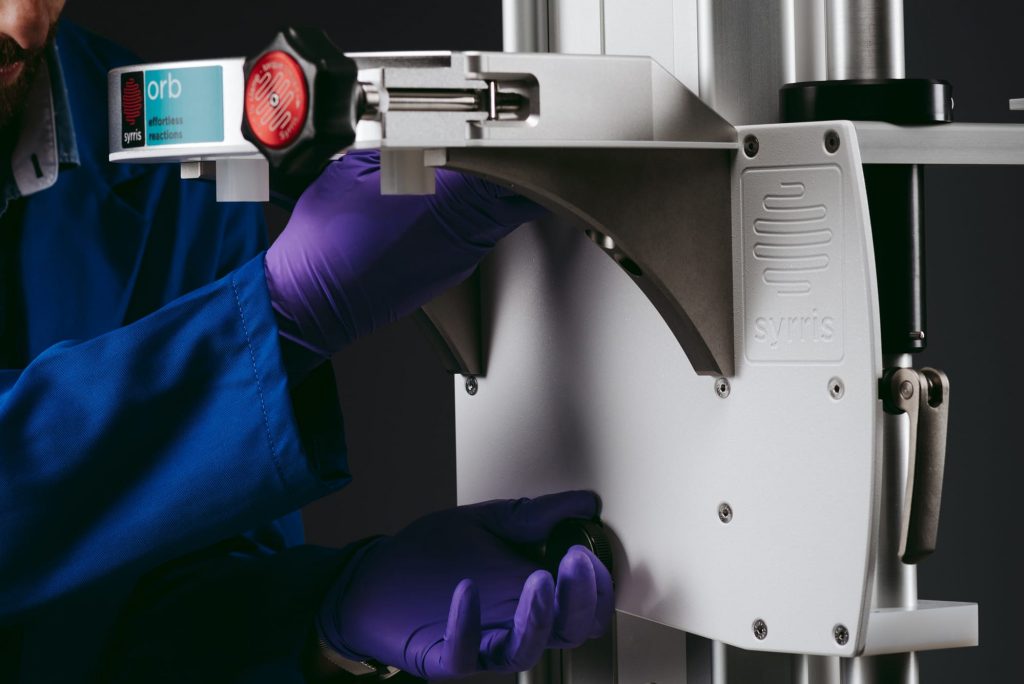 A photograph of a chemist easily adjusting the vessel height on an Orb Jacketed Reactor