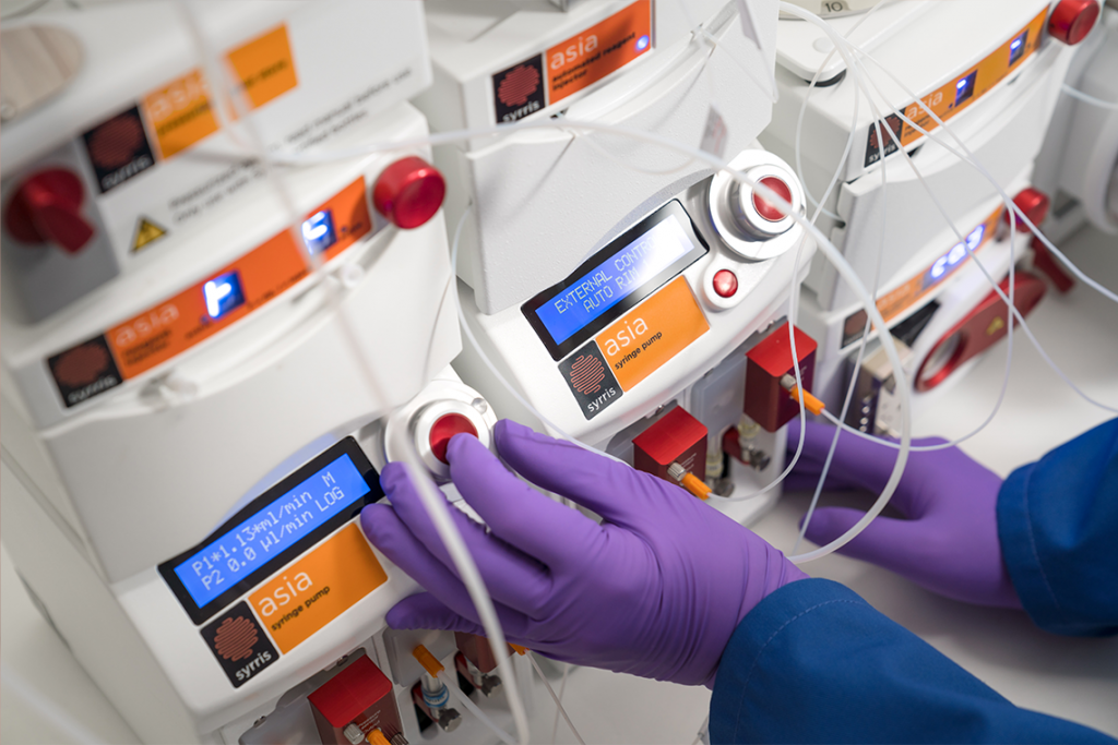 Syrris Asia chemist in lab with syringe pump